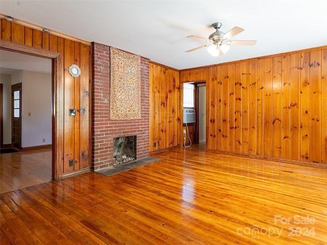 unfurnished living room featuring ceiling fan, a brick fireplace, brick wall, and light hardwood / wood-style floors