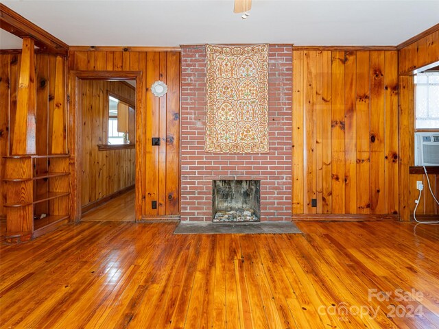 unfurnished living room featuring brick wall, a healthy amount of sunlight, and hardwood / wood-style flooring