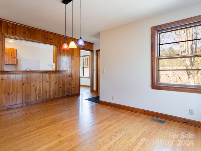 unfurnished room featuring wood walls and light wood-type flooring