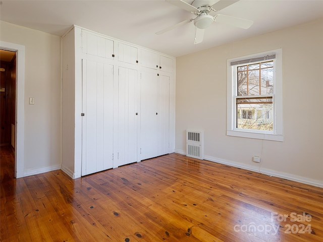 unfurnished bedroom featuring ceiling fan, a closet, and dark wood-type flooring