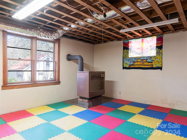 basement featuring a wood stove and a healthy amount of sunlight