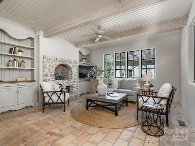 sitting room with ceiling fan, wood ceiling, beamed ceiling, and a brick fireplace