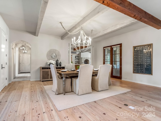 dining space with beamed ceiling, an inviting chandelier, and light hardwood / wood-style flooring