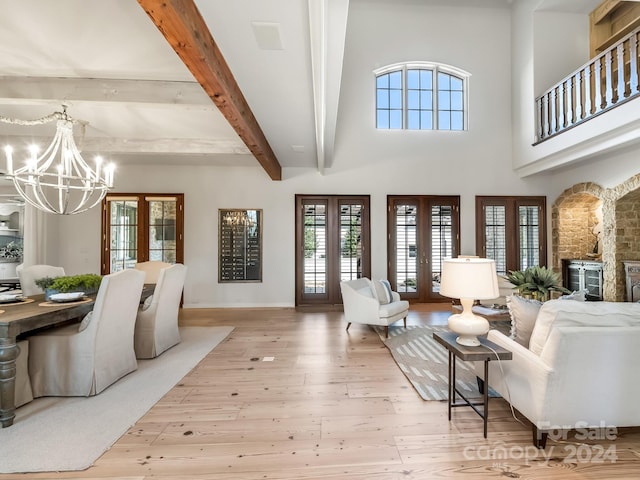 living room with beamed ceiling, french doors, a chandelier, and light hardwood / wood-style flooring