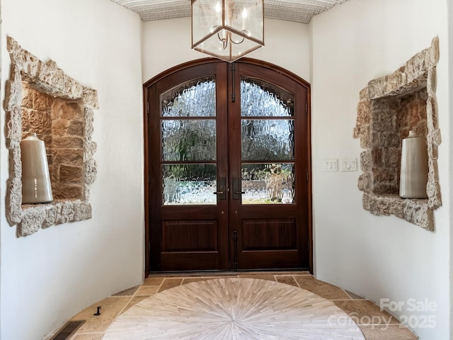 entrance foyer featuring visible vents, a chandelier, and french doors