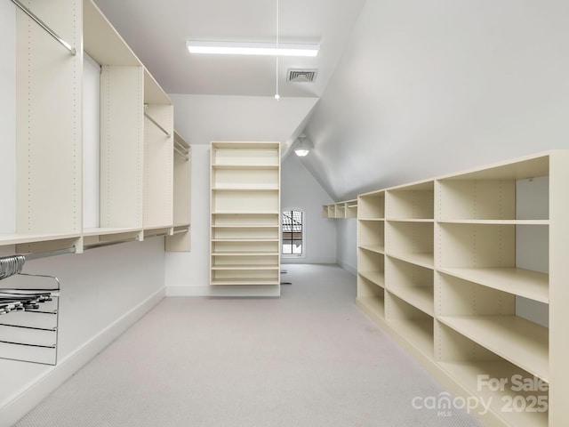 spacious closet featuring light carpet, vaulted ceiling, and visible vents