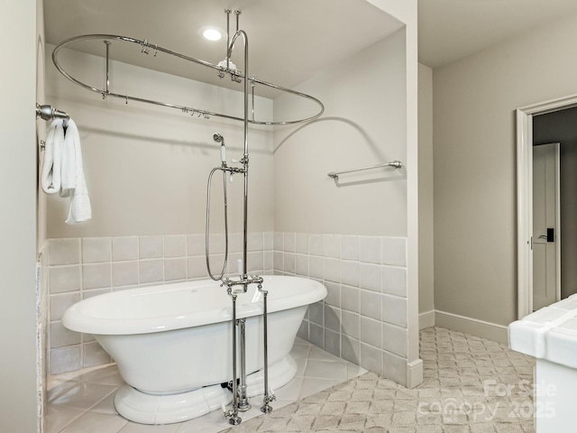 bathroom featuring a freestanding tub, wainscoting, tile walls, and tile patterned floors