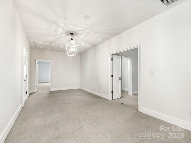 spare room with light carpet, attic access, visible vents, and baseboards