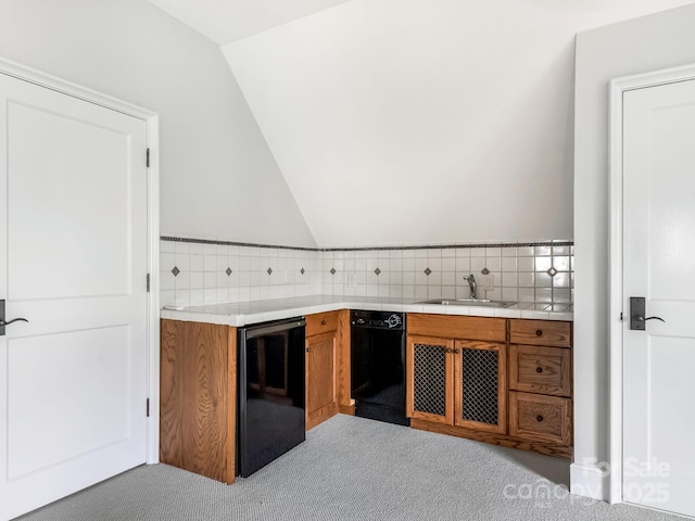 kitchen with brown cabinetry, vaulted ceiling, light countertops, and a sink