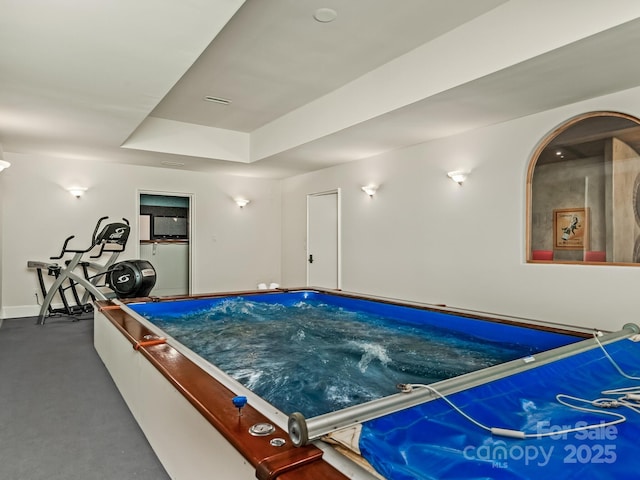 recreation room featuring baseboards and a tray ceiling