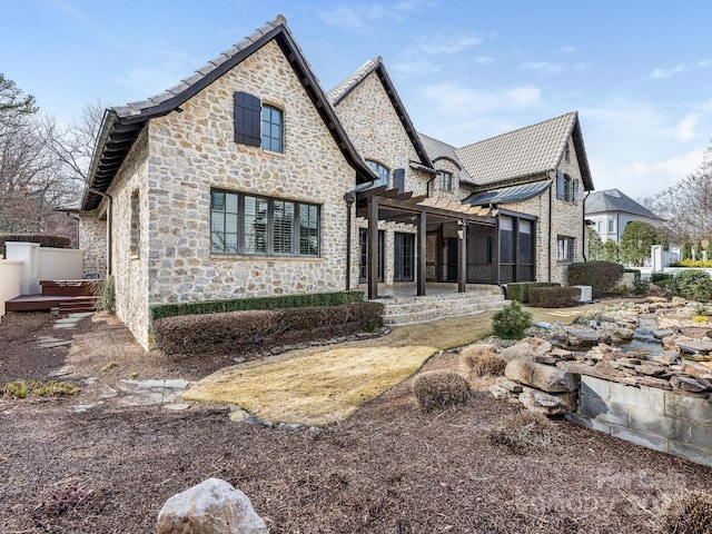 view of front facade with stone siding, a tile roof, a patio, and a pergola