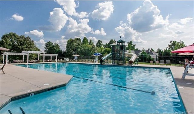 view of swimming pool with a pergola and a water slide