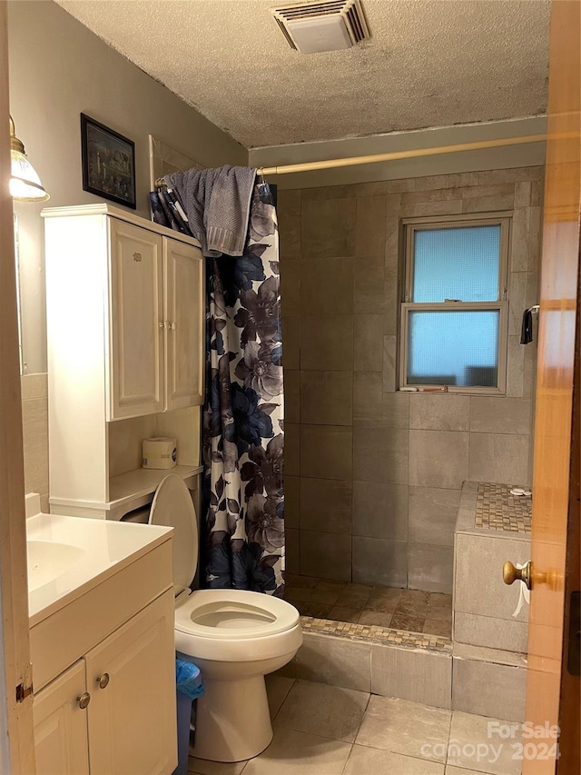 bathroom featuring a shower with curtain, toilet, vanity, a textured ceiling, and tile floors