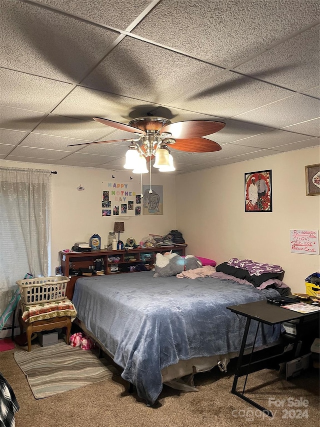 carpeted bedroom with ceiling fan, a drop ceiling, and a baseboard heating unit