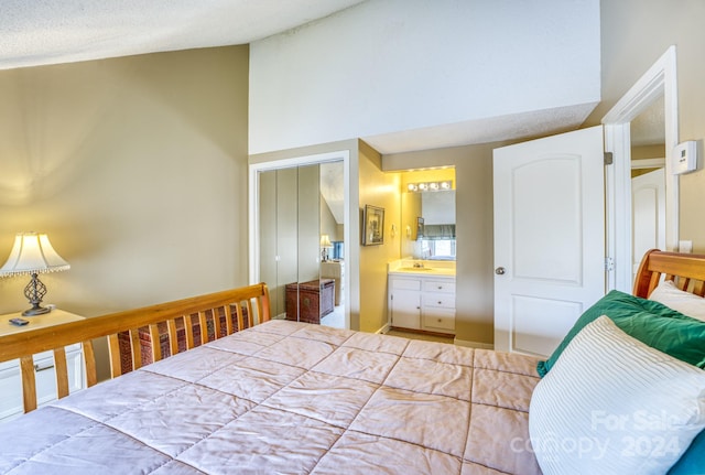 bedroom featuring ensuite bathroom, vaulted ceiling, a closet, and sink