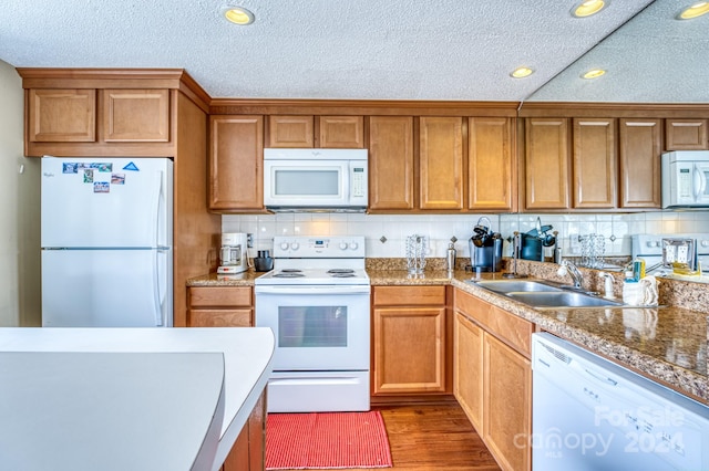 kitchen with backsplash, light hardwood / wood-style flooring, white appliances, and sink