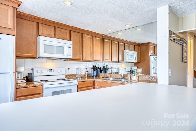 kitchen with sink, white appliances, backsplash, and a textured ceiling