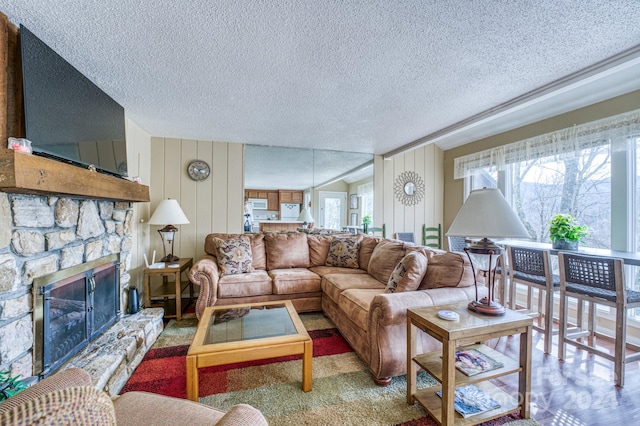 living room featuring light colored carpet, wood walls, a textured ceiling, and a fireplace