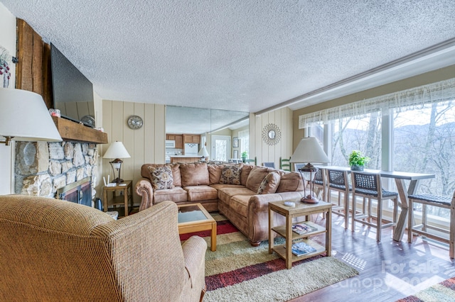 living room featuring a stone fireplace and a textured ceiling