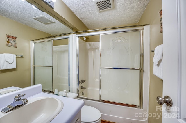 full bathroom featuring toilet, shower / bath combination with glass door, a textured ceiling, and vanity