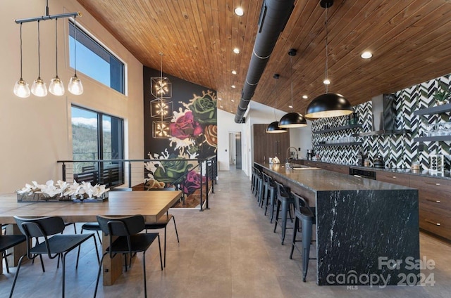 dining space featuring sink, a high ceiling, and wooden ceiling