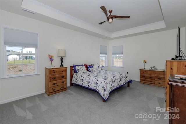 carpeted bedroom with ornamental molding, ceiling fan, and a tray ceiling