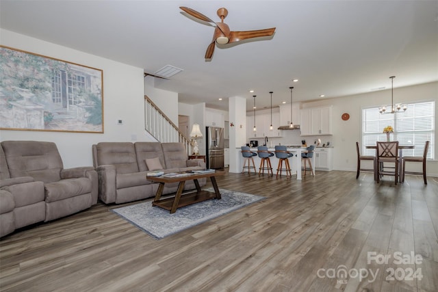 living room featuring ceiling fan with notable chandelier and light hardwood / wood-style floors