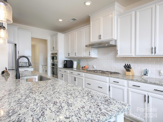 kitchen featuring hanging light fixtures, sink, and white cabinets