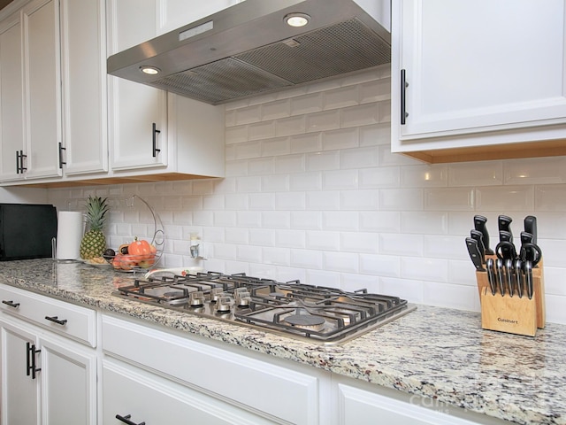 kitchen featuring tasteful backsplash, white cabinets, and wall chimney exhaust hood