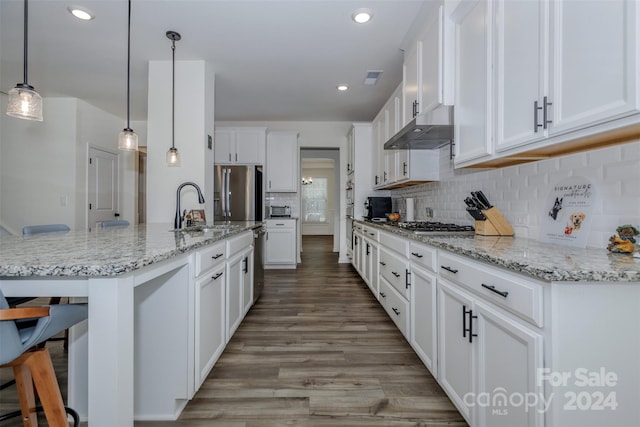 kitchen featuring sink, a breakfast bar area, white cabinetry, decorative light fixtures, and a kitchen island with sink