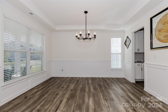 unfurnished dining area featuring an inviting chandelier, plenty of natural light, and a raised ceiling