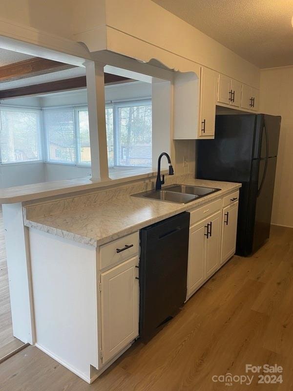 kitchen with white cabinetry, light hardwood / wood-style floors, sink, and black appliances