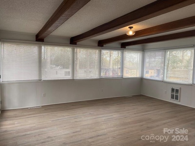 unfurnished sunroom featuring beamed ceiling