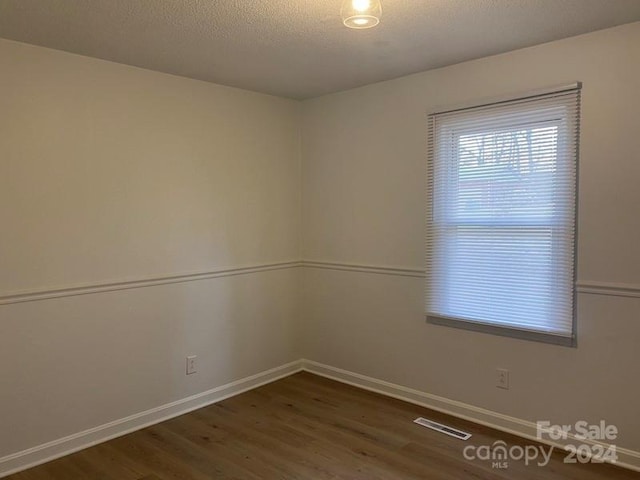 unfurnished room featuring dark hardwood / wood-style flooring and a textured ceiling