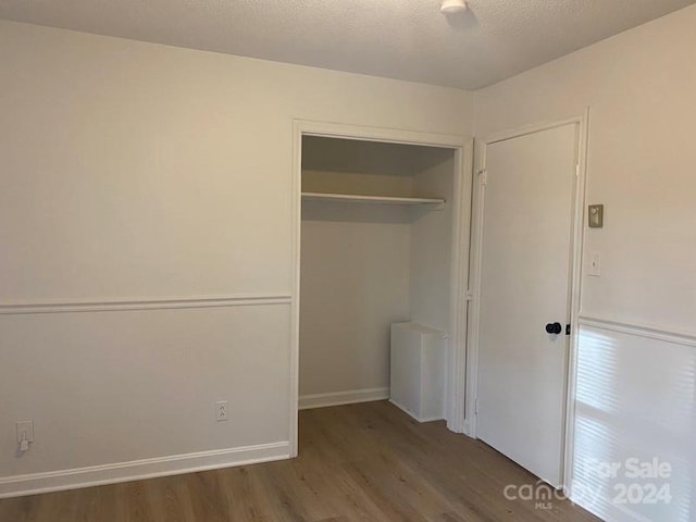 unfurnished bedroom featuring a closet and dark wood-type flooring