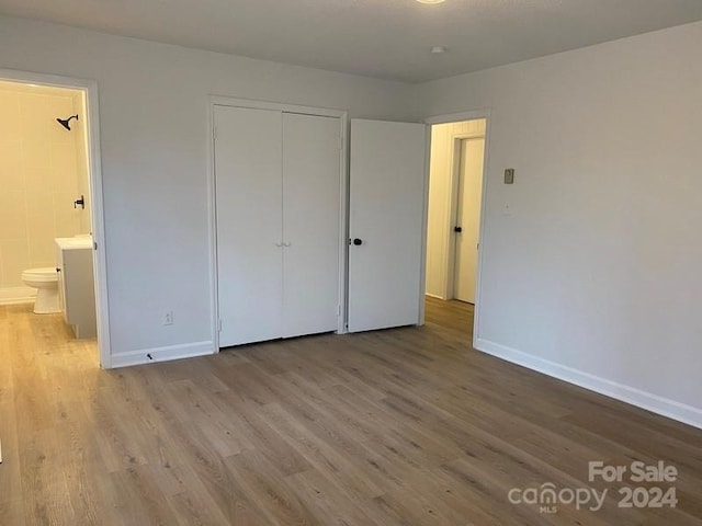 unfurnished bedroom with connected bathroom, a closet, and light hardwood / wood-style flooring