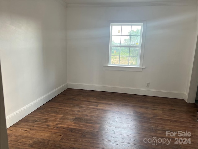 spare room featuring dark hardwood / wood-style floors and crown molding