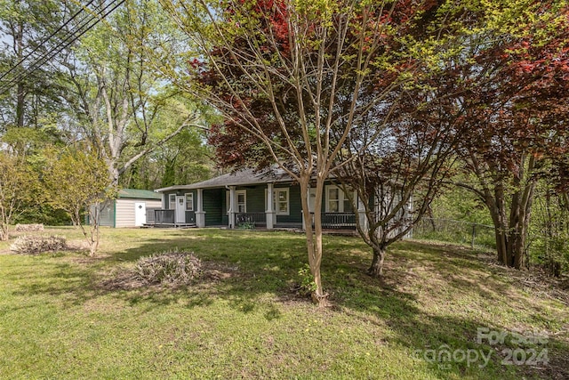 ranch-style home featuring a porch, an outdoor structure, and a front lawn