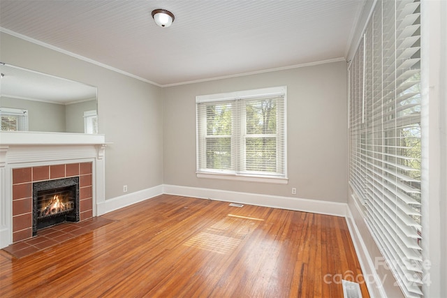 unfurnished living room featuring crown molding, a tile fireplace, and hardwood / wood-style floors