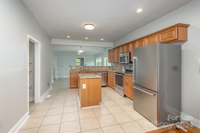 kitchen featuring light stone counters, a center island, tasteful backsplash, stainless steel appliances, and kitchen peninsula