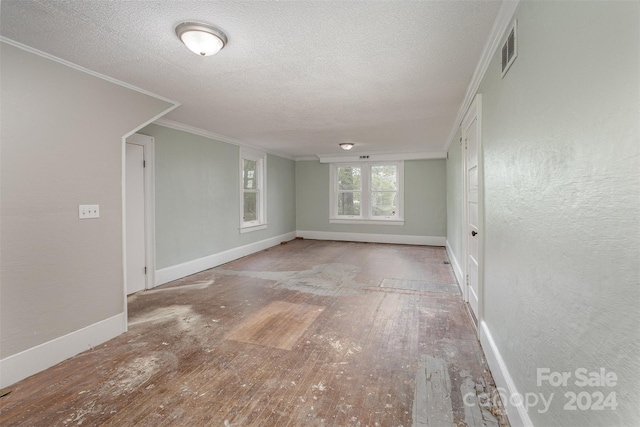 empty room with ornamental molding, light wood-type flooring, and a textured ceiling