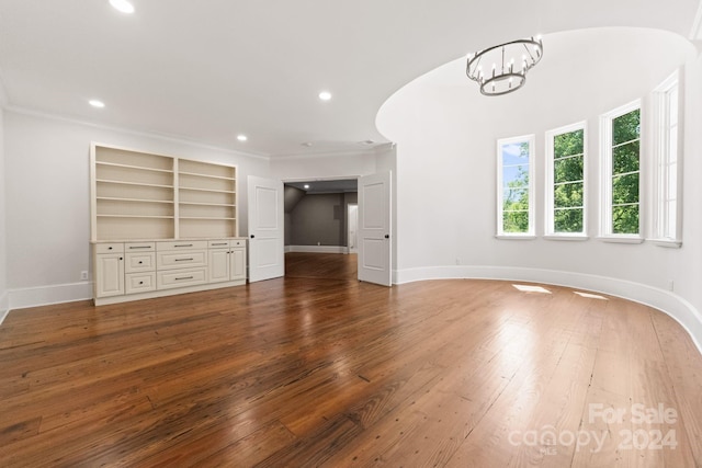 unfurnished bedroom with wood-type flooring, crown molding, and a chandelier