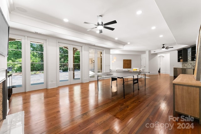 recreation room with a large fireplace, wood-type flooring, ceiling fan, and french doors