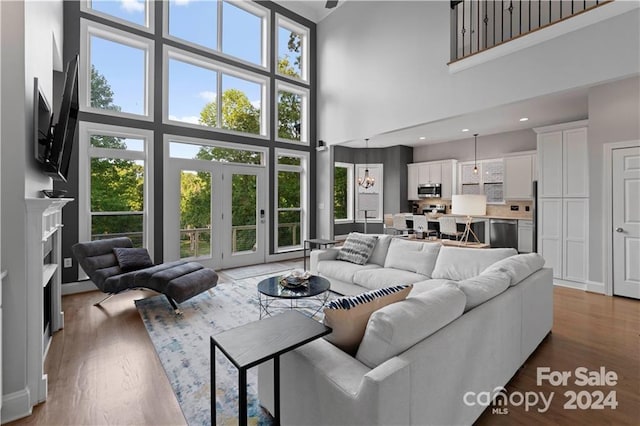 living room with a towering ceiling, a wealth of natural light, and light hardwood / wood-style floors