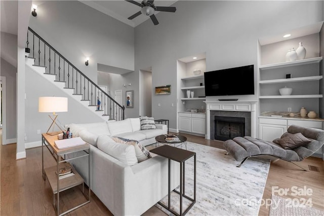 living room with hardwood / wood-style floors, ceiling fan, built in shelves, and a fireplace