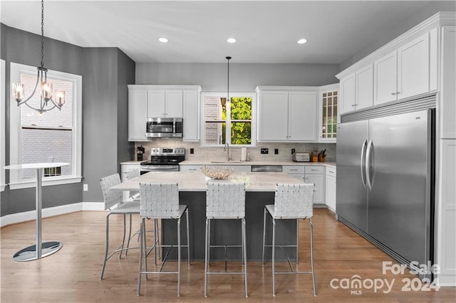 kitchen featuring appliances with stainless steel finishes, white cabinets, a kitchen island, and dark hardwood / wood-style flooring