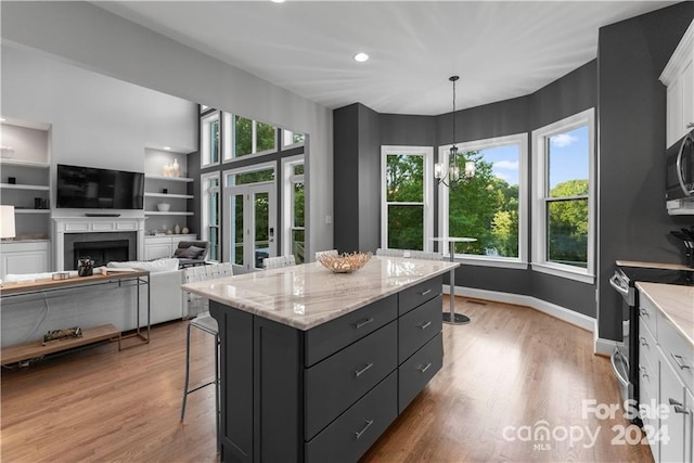 kitchen with electric range oven, hanging light fixtures, white cabinetry, and light hardwood / wood-style floors