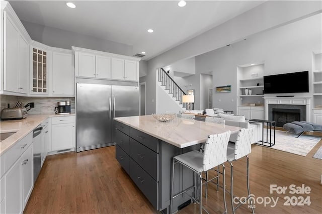 kitchen featuring appliances with stainless steel finishes, a kitchen island, a breakfast bar area, white cabinetry, and dark hardwood / wood-style floors