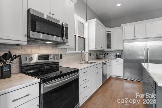 kitchen with pendant lighting, tasteful backsplash, stainless steel appliances, white cabinetry, and dark hardwood / wood-style floors