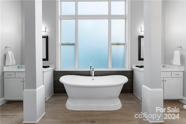 bathroom with tile walls, vanity, and a tub